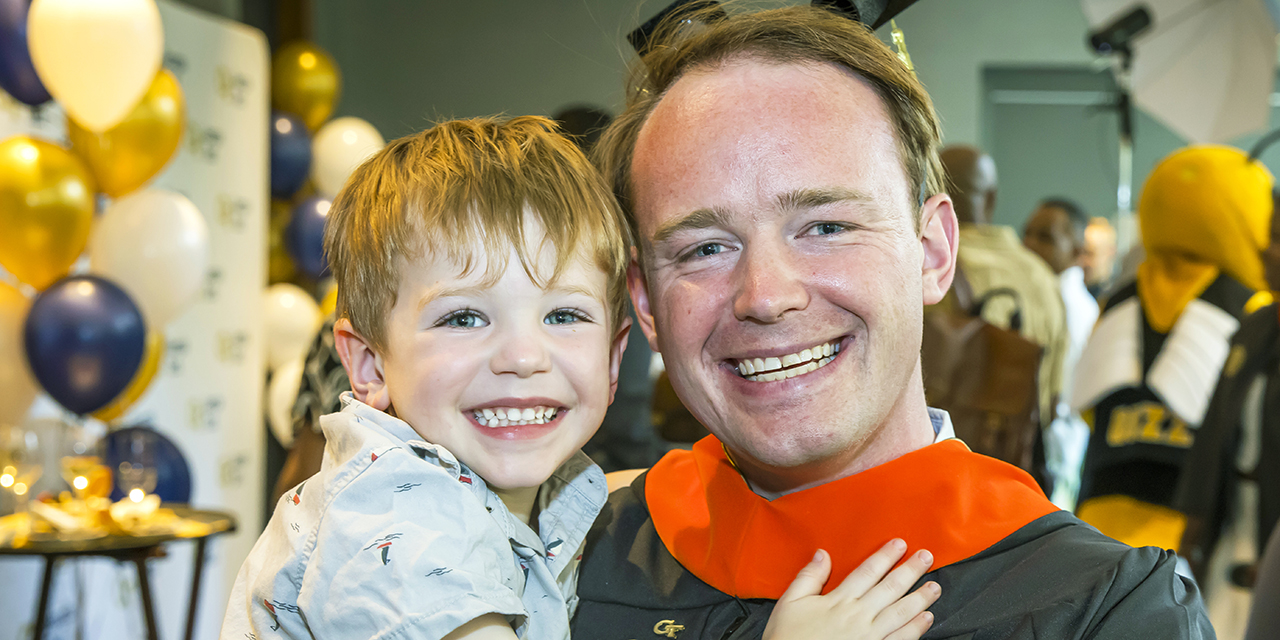 man holding child at graduation event